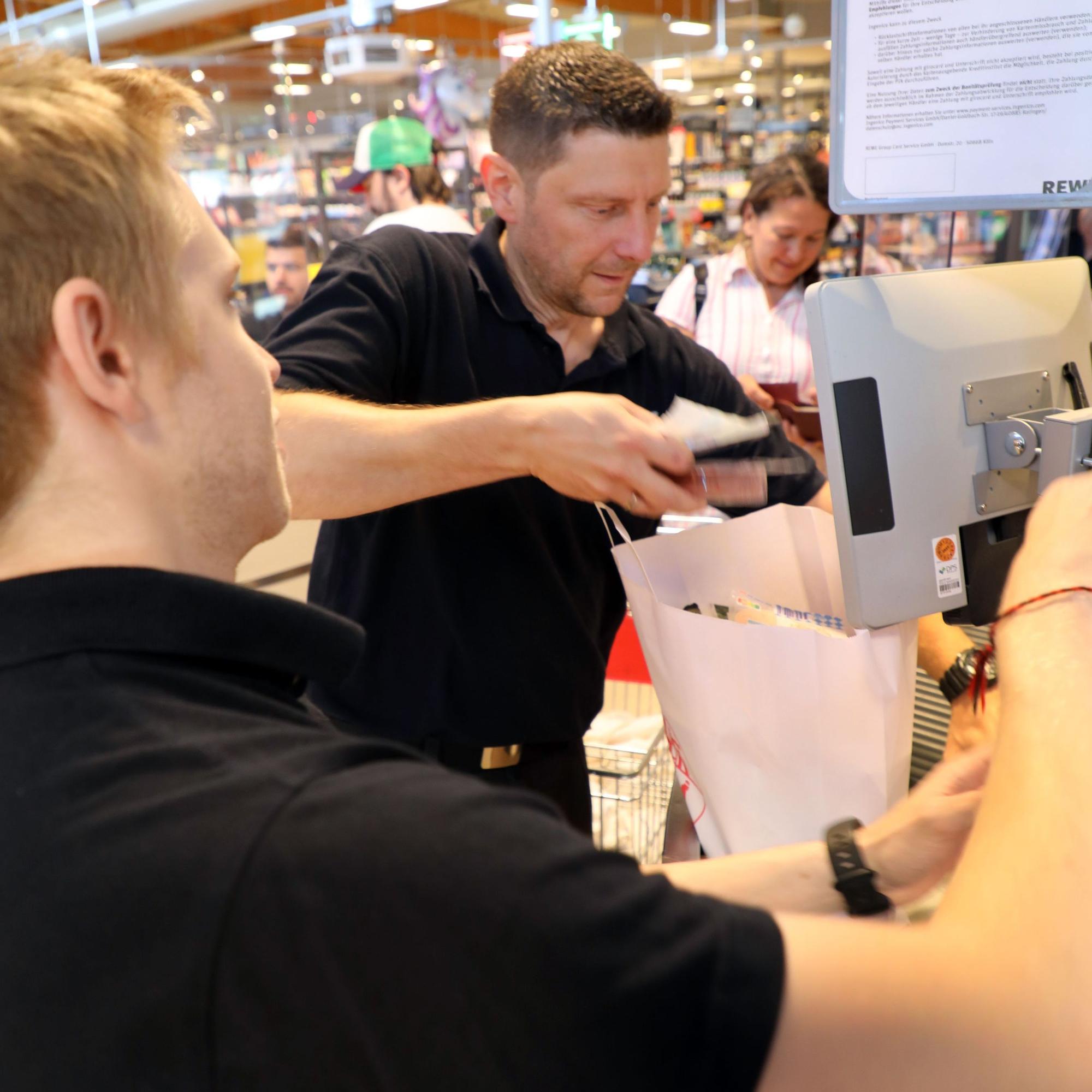Zwei Feuerwehrleute packen Einkäufe in eine Papiertragetasche.