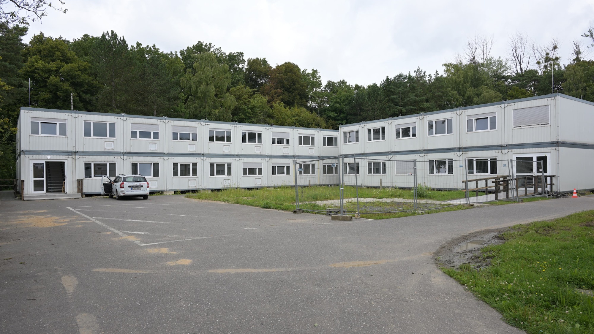 Man sieht zwei über Eck gebaute Riegel von grauen Containerbauten.