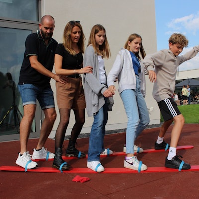 Vier Besucher versuchen sich, festgeschnallt auf zwei Brettern, fortzubewegen.