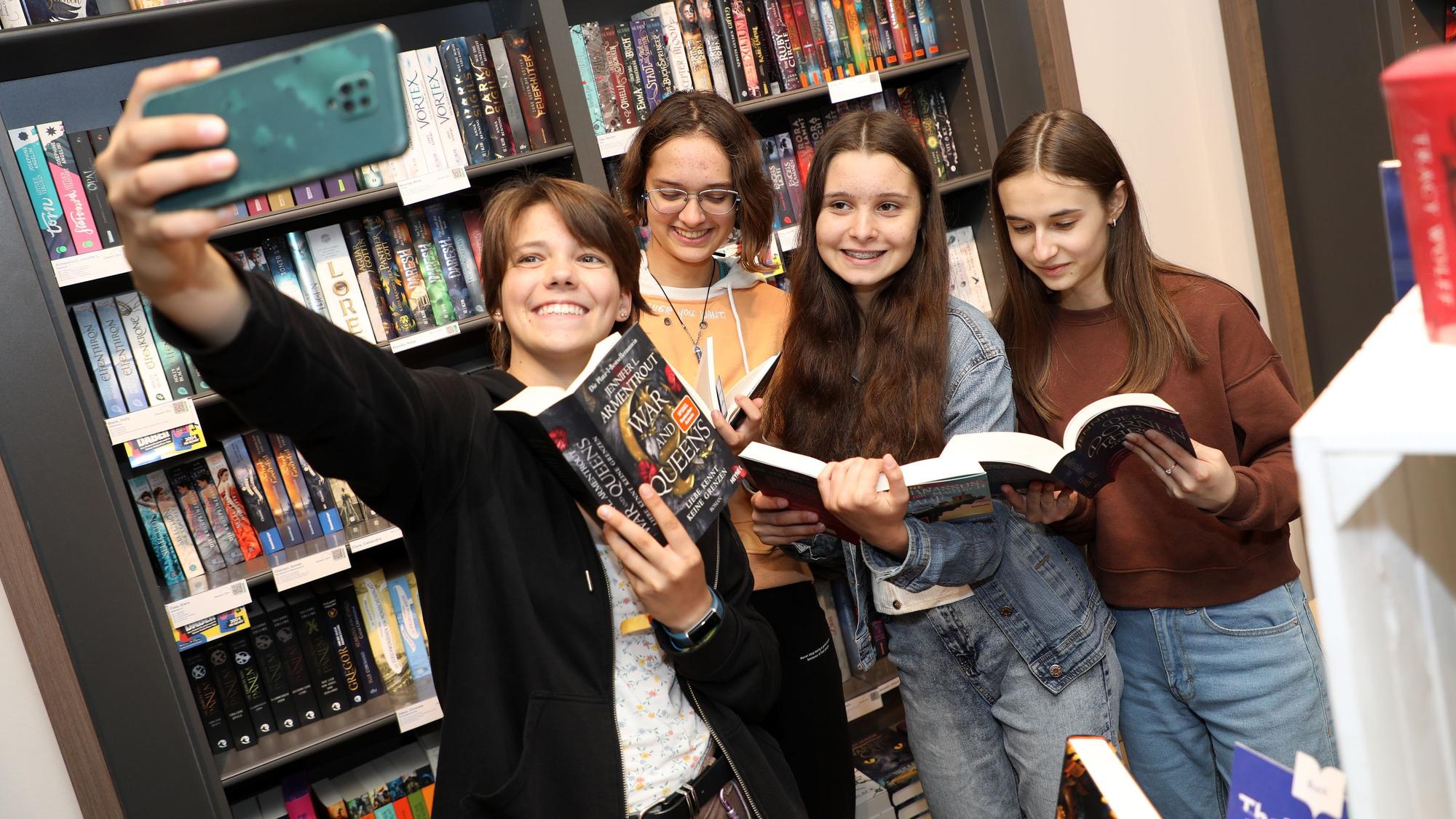 Vor einem Bücherregal in der Buchhandlung machen die vier Mädchen der Rallye-Gruppe ein Selfie mit Büchern.