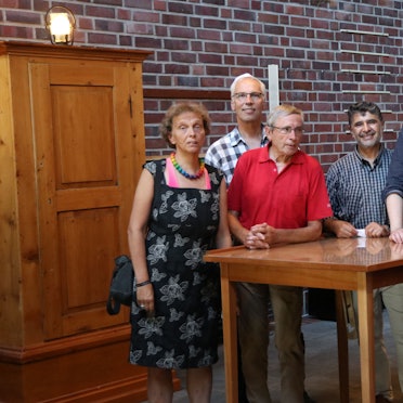 Einige Menschen stehen um einen Tisch herum.