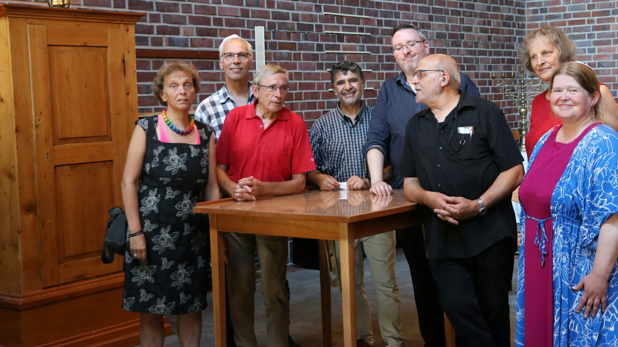 Einige Menschen stehen um einen Tisch herum.