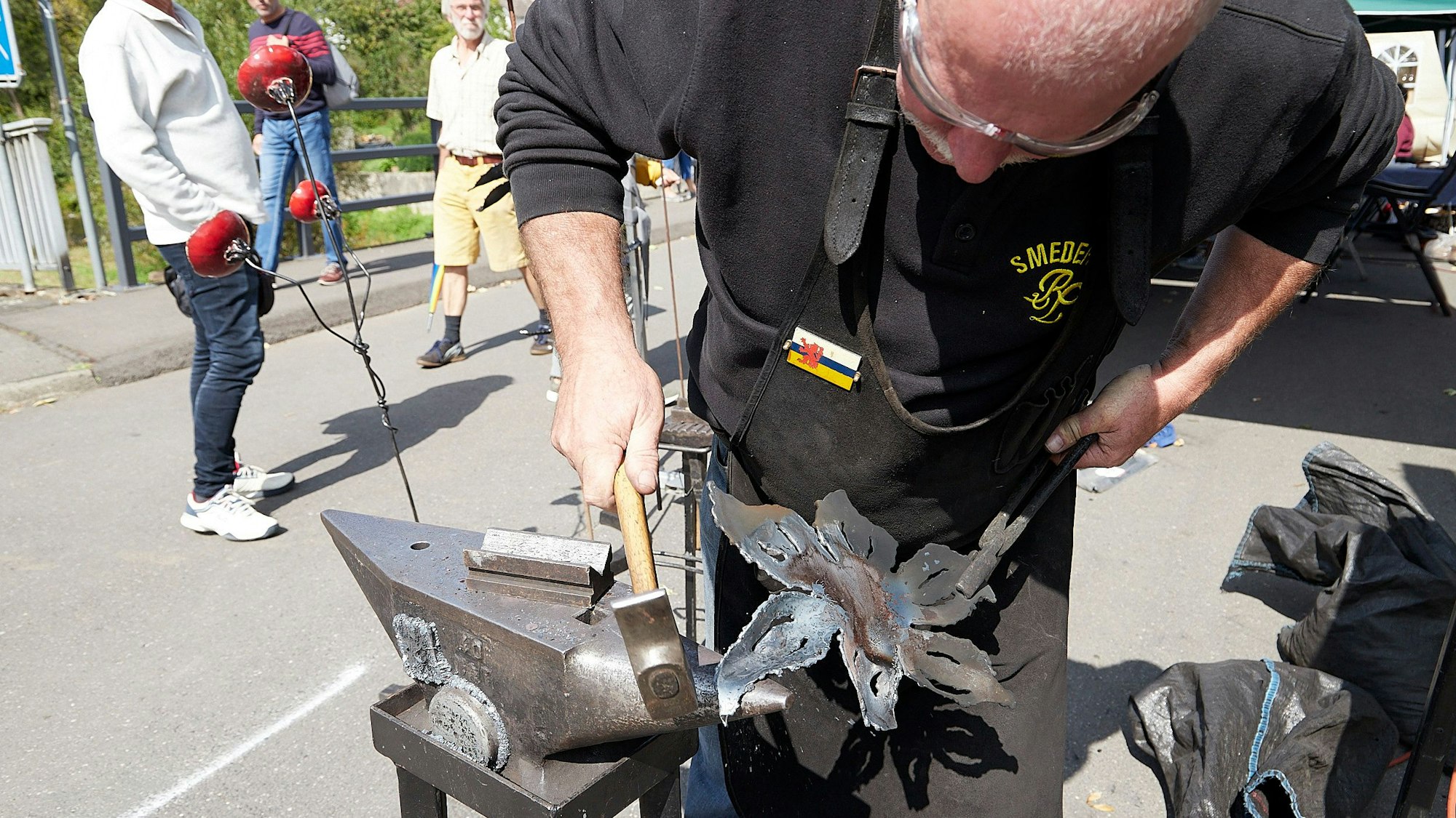 Ein Mann bearbeitet Metall auf einem Amboss.