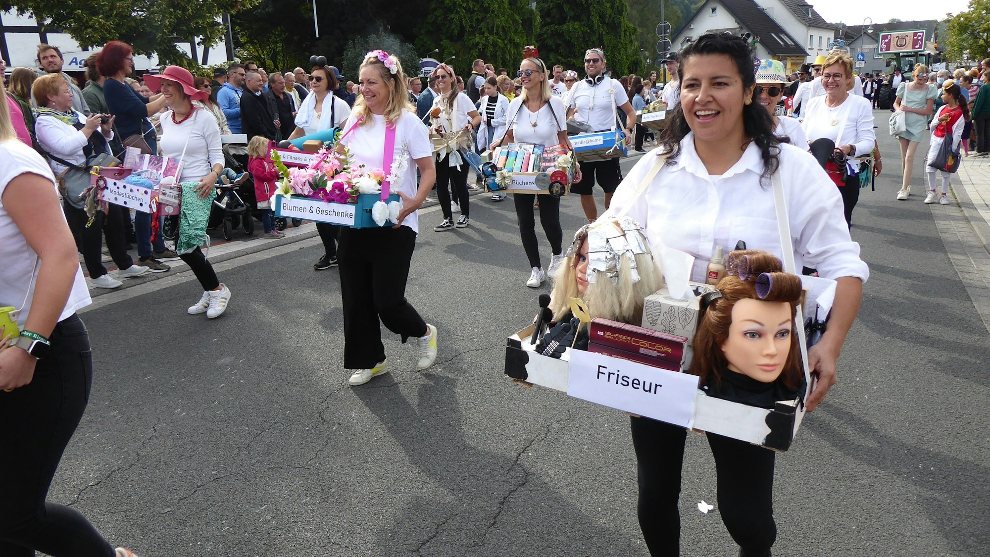 Frauen und Männer der Fußgruppe bieten Dienstleistungen aus dem Bauchladen heraus an.