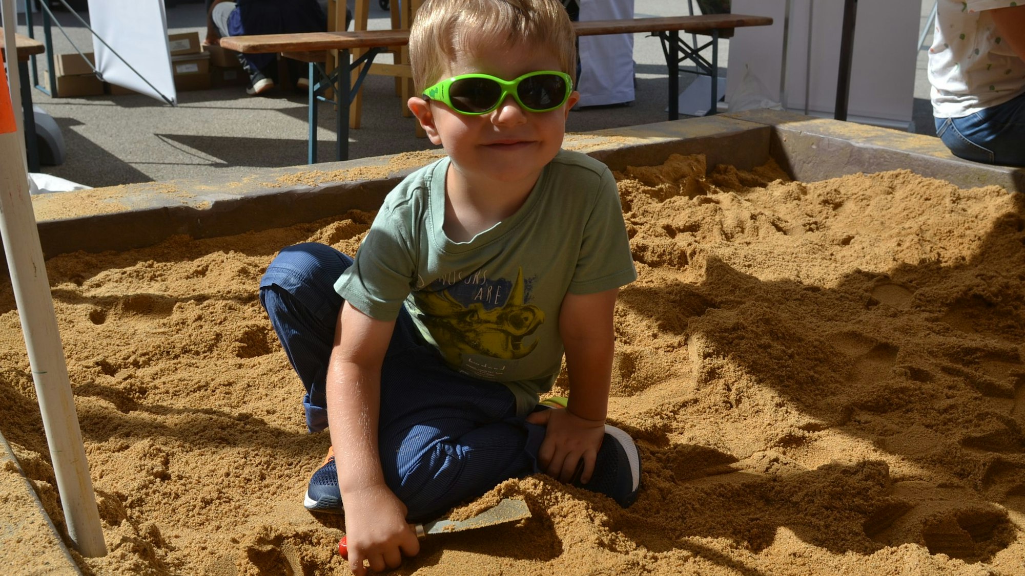 Ein kleiner Junge sucht beim Mittelalterfest als Archäologe nach einem Schatz im Sandkasten.