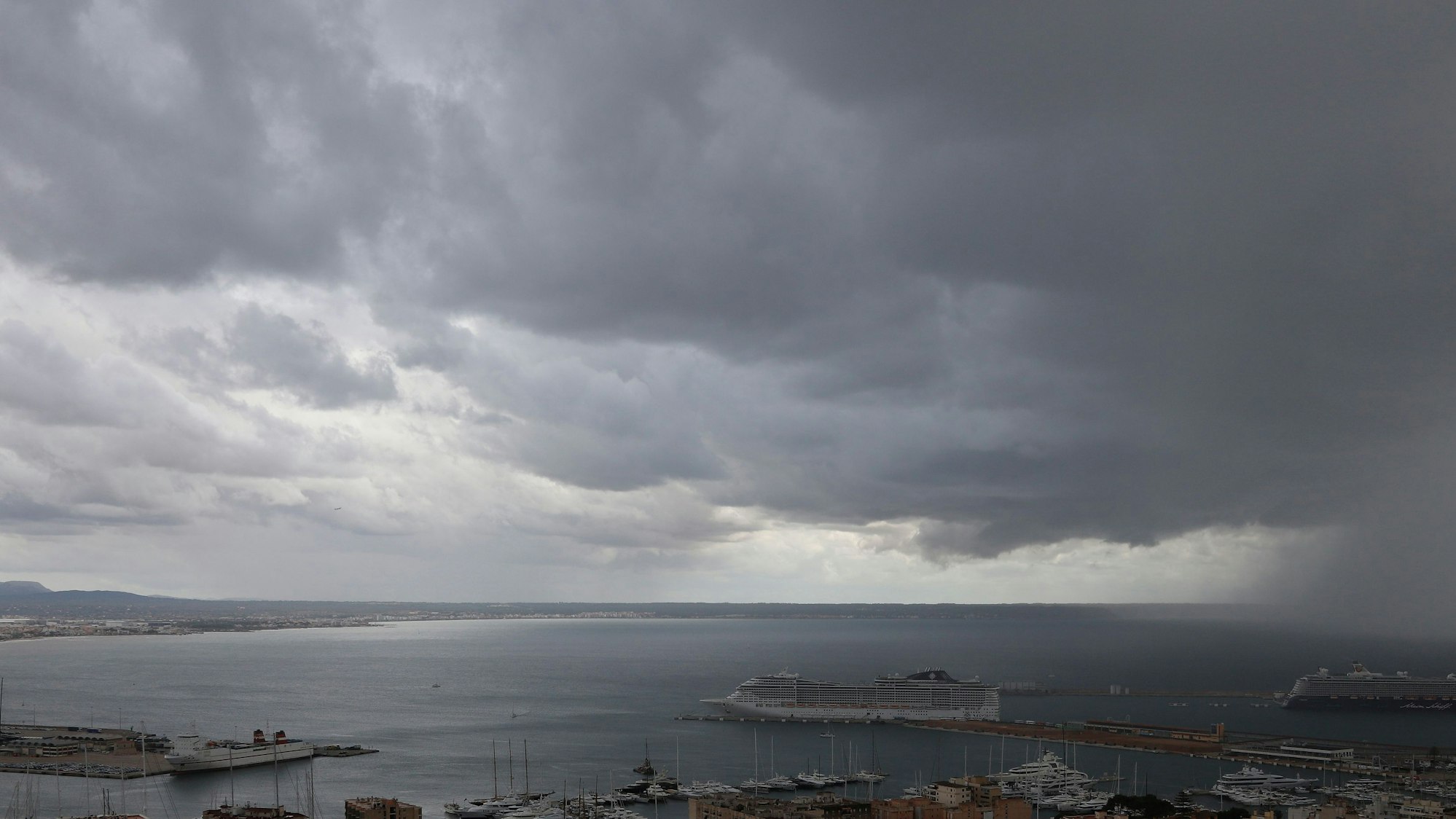 Dunkle Regenwolken hängen über der Bucht und einem Hafen auf Mallorca (Symbolbild).