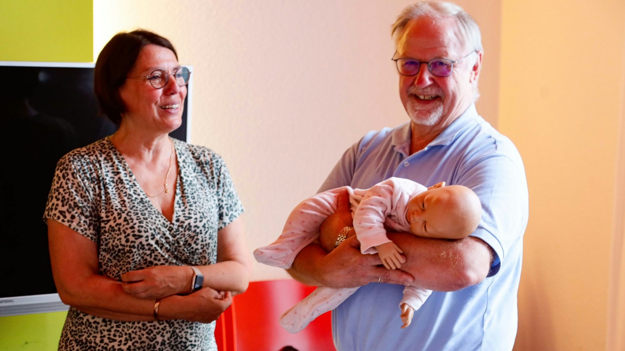 Kursleiterin Dagmar Stapper zeigt einem Teilnehmer, wie man ein Baby hält.