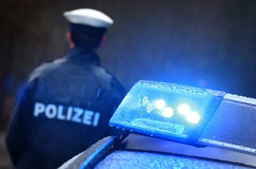 Symbolbild zeigt Blaulicht und die Rückseite eines uniformierten Polizisten.