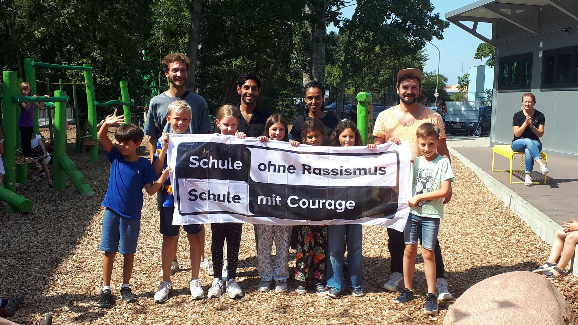 Schülerinnen und Schüler der GGS halten ein Transparent hoch mit dem Schriftzug „Schule ohne Rassismus, Schule mit Courage“.