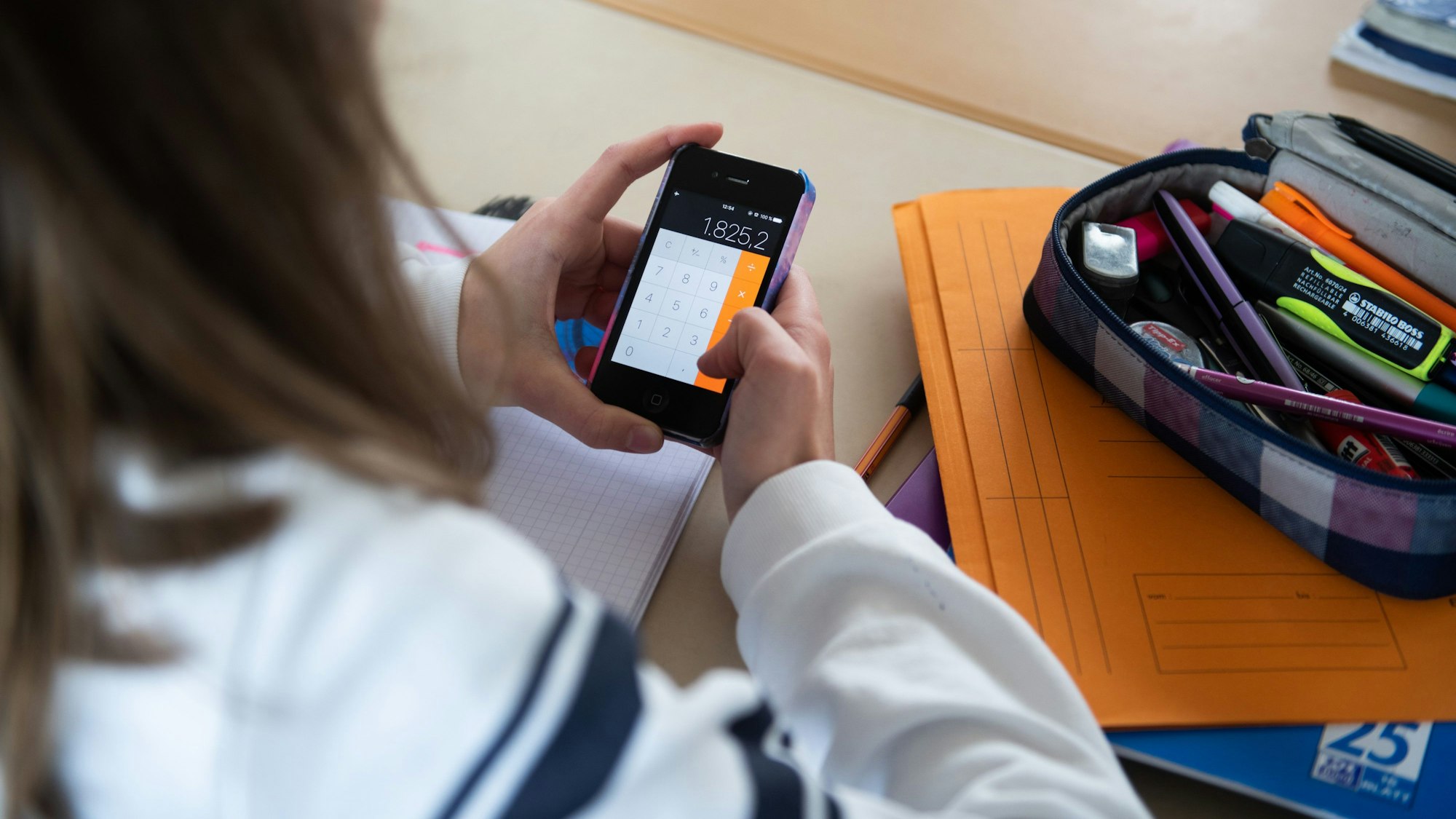 Eine Schülerin benutzt den Taschenrechner ihres Smartphones.