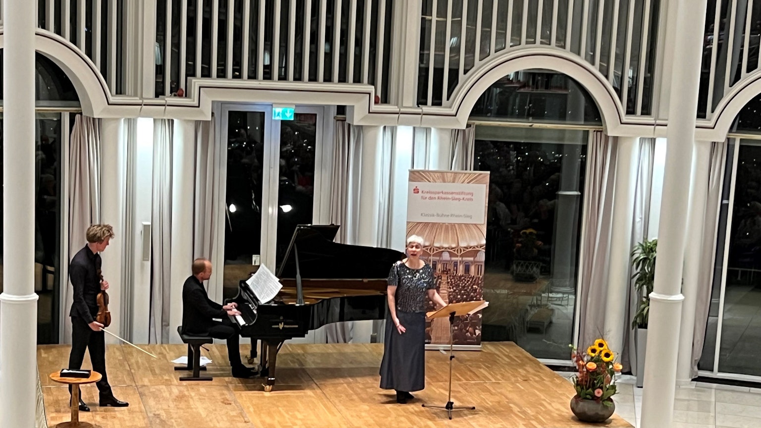 Auf der Bühne der Rotunde auf dem Petersberg musizieren ein Violinist, ein Pianist und eine Sängerin.