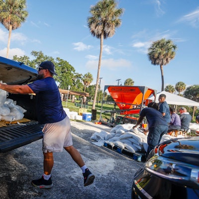 28.08.2023, USA, Tampa: David Fuentes lädt vor der Ankunft des Tropensturms Idalia im MacFarlane Park in Tampa Sandsäcke auf ein Auto. Der US-Bundesstaat Florida bereitet sich auf die Ankunft eines Hurrikans vor. Foto: Ivy Ceballo/Tampa Bay Times/AP/dpa - ACHTUNG: Nur zur redaktionellen Verwendung und nur mit vollständiger Nennung des vorstehenden Credits +++ dpa-Bildfunk +++