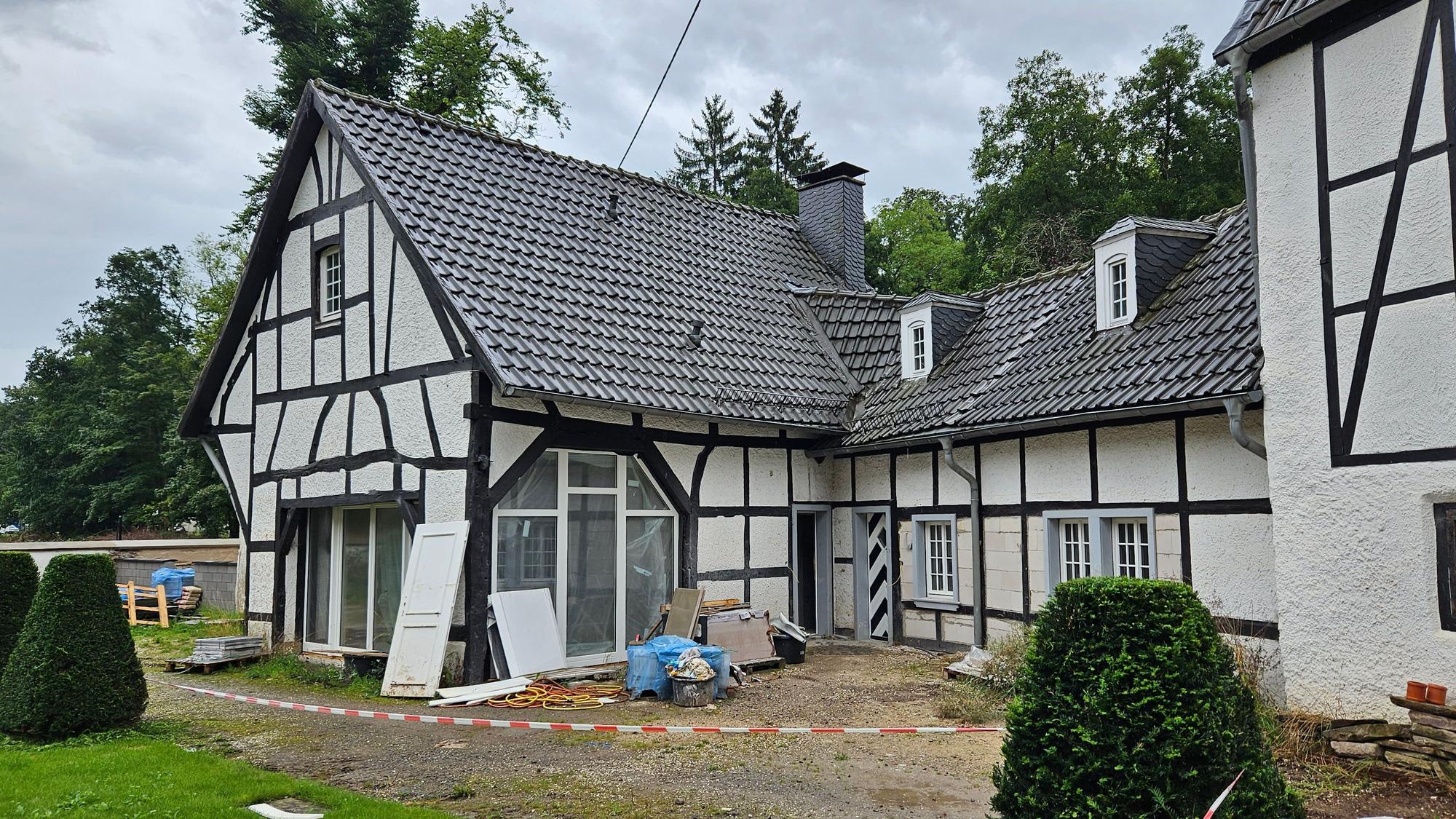 Vor einem Fachwerkhaus stehen noch Reste von Bauschutt.