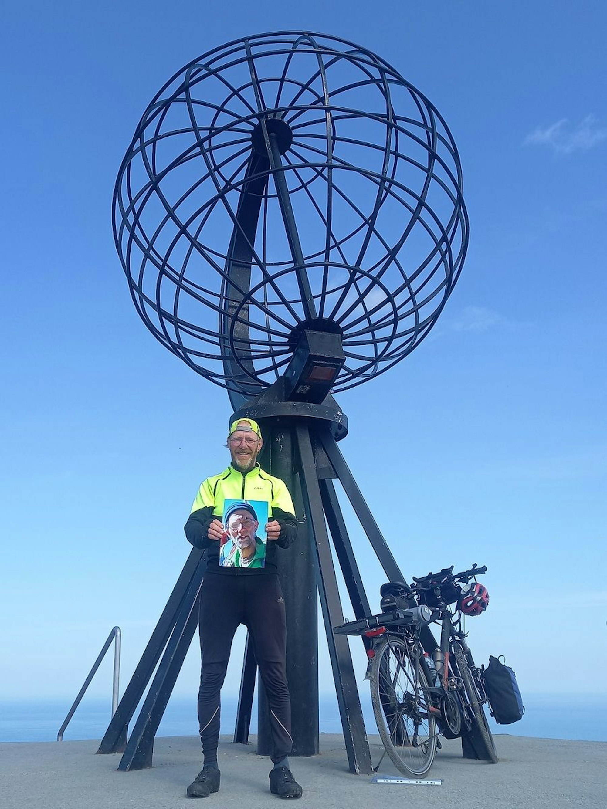 Ein Mann steht am Nordkap mit einem Foto in den Händen.