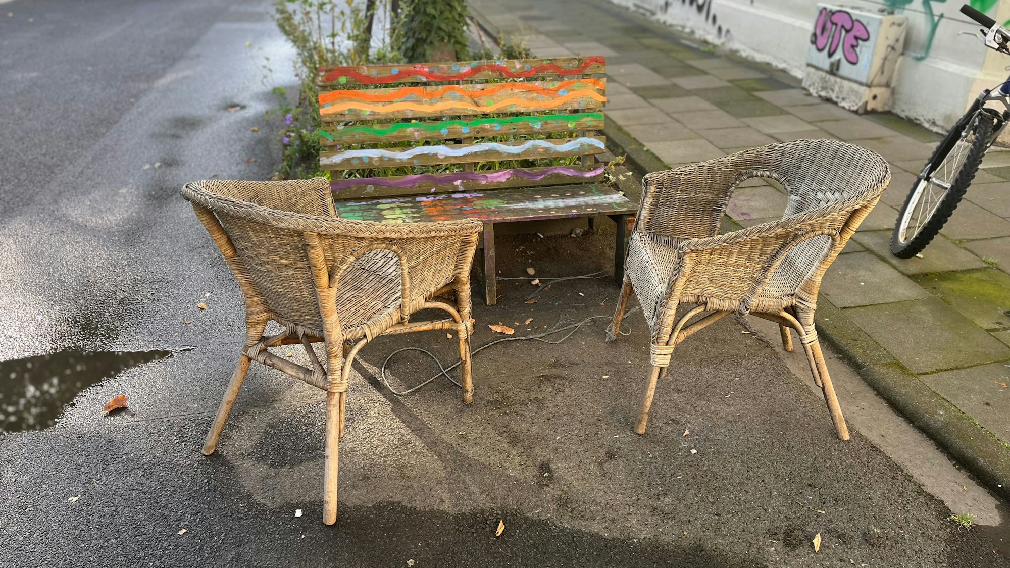 Eine bunte Bank steht am Straßenrand.