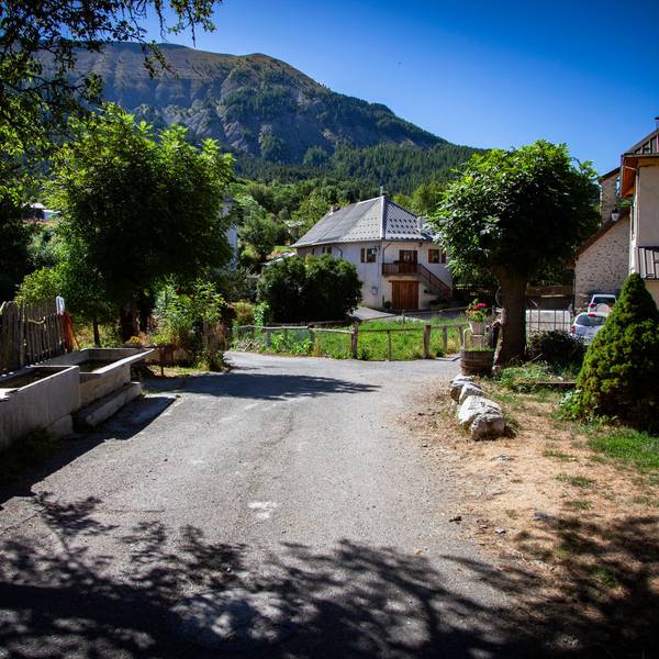 Eine Straße im französischen Dorf Le Vernet, in dem der zweijährige Émile zuletzt gesehen wurde. Am Straßenrand stehen mehrere Häuser, im Hintergrund sind die Alpen zu sehen.