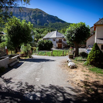 Eine Straße im französischen Dorf Le Vernet, in dem der zweijährige Émile zuletzt gesehen wurde. Am Straßenrand stehen mehrere Häuser, im Hintergrund sind die Alpen zu sehen.