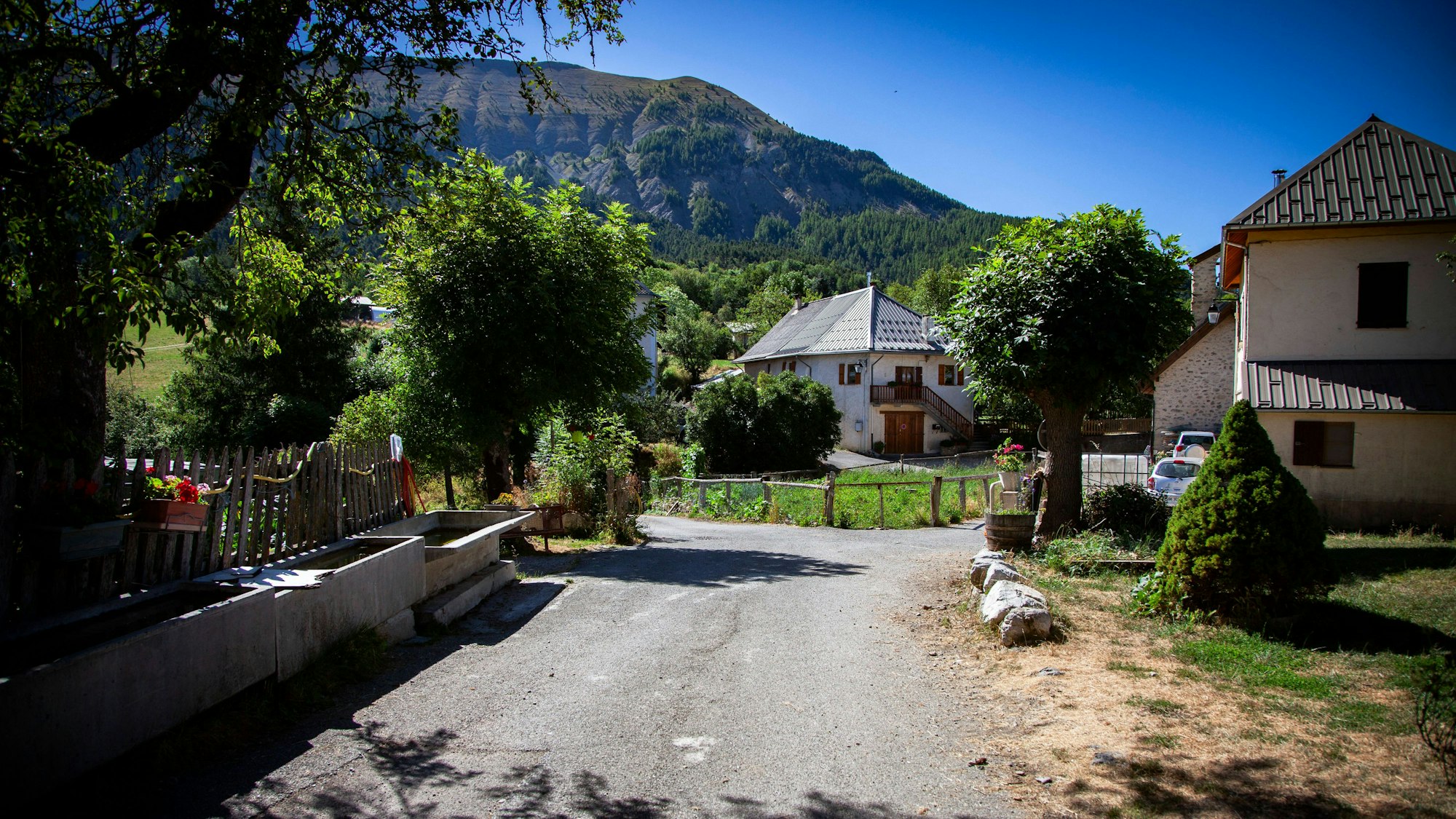 Eine Straße im französischen Dorf Le Vernet, in dem der zweijährige Émile zuletzt gesehen wurde. Am Straßenrand stehen mehrere Häuser, im Hintergrund sind die Alpen zu sehen.