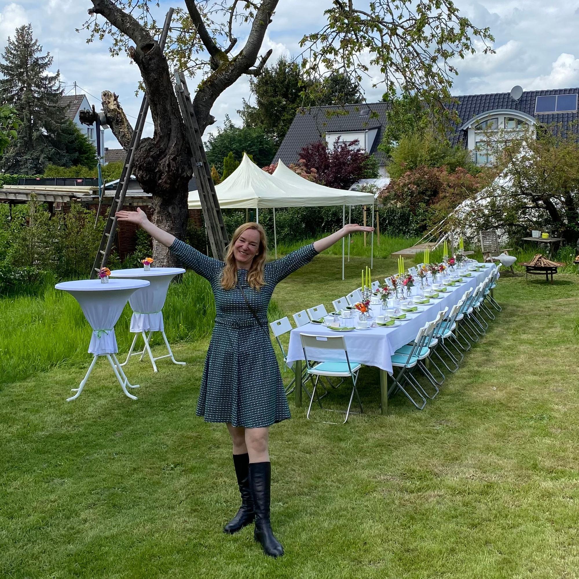 Doe Gastgeberin steht vor einem gedeckten Tisch.