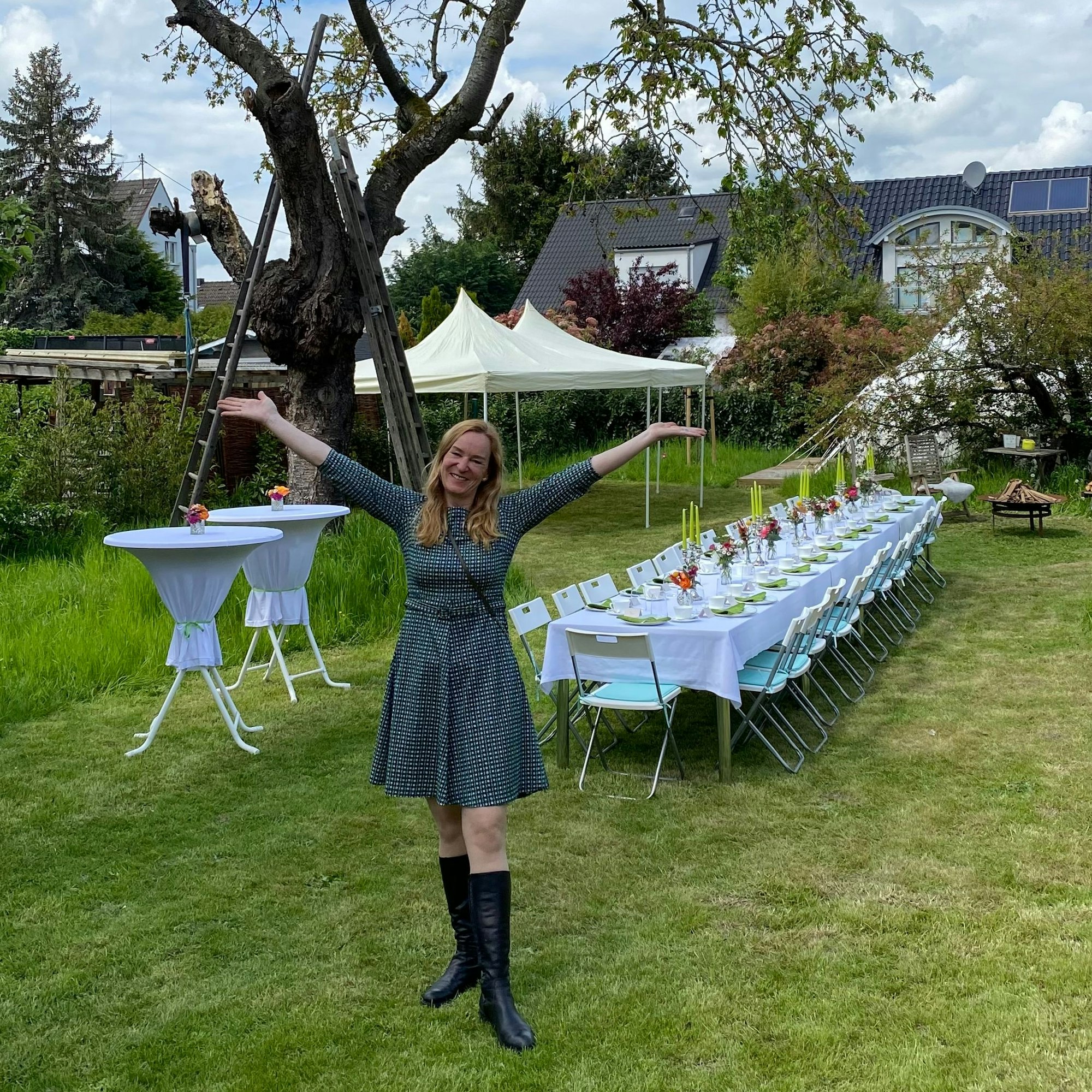 Doe Gastgeberin steht vor einem gedeckten Tisch.
