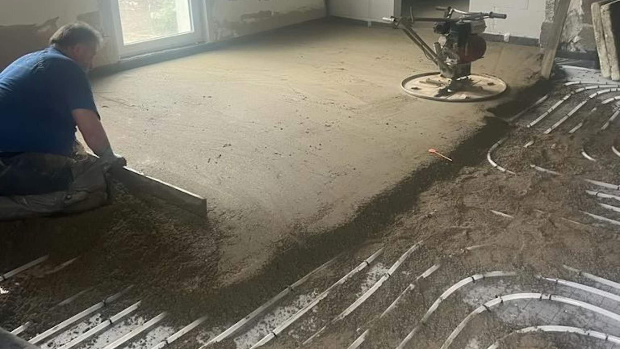 Das Bild zeigt einen Handwerker, der den Estrich in die Waage bringt.