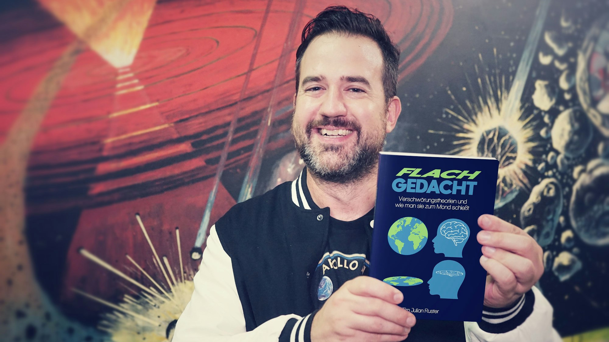 Ein Mann hält ein Buch im Arm.