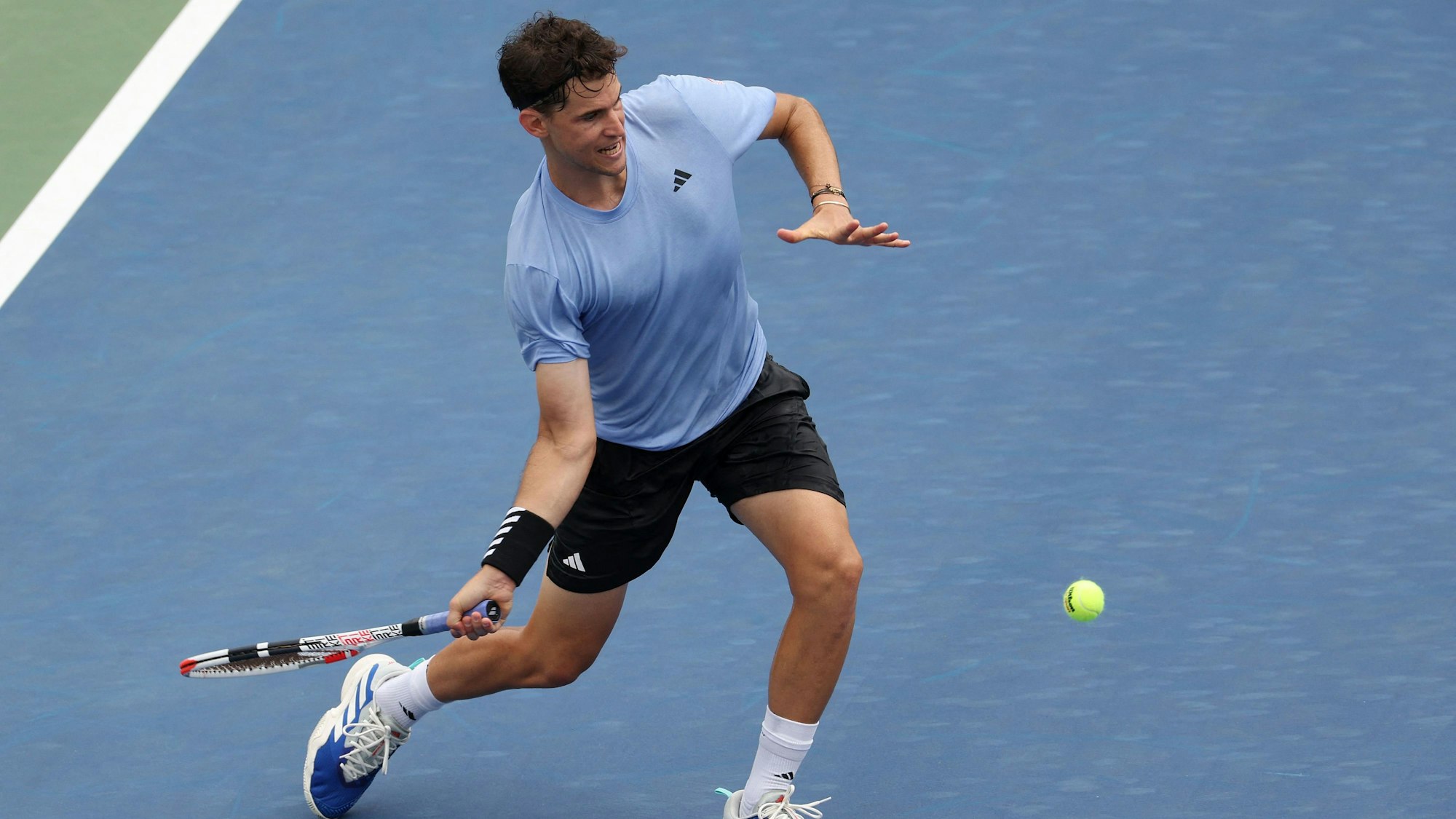 Der österreichische Tennisspieler Dominic Thiem schlägt beim Erstrunden-Spiel der US Open gegen Alexander Bublik den Ball auf dem blauen Hartplatz.