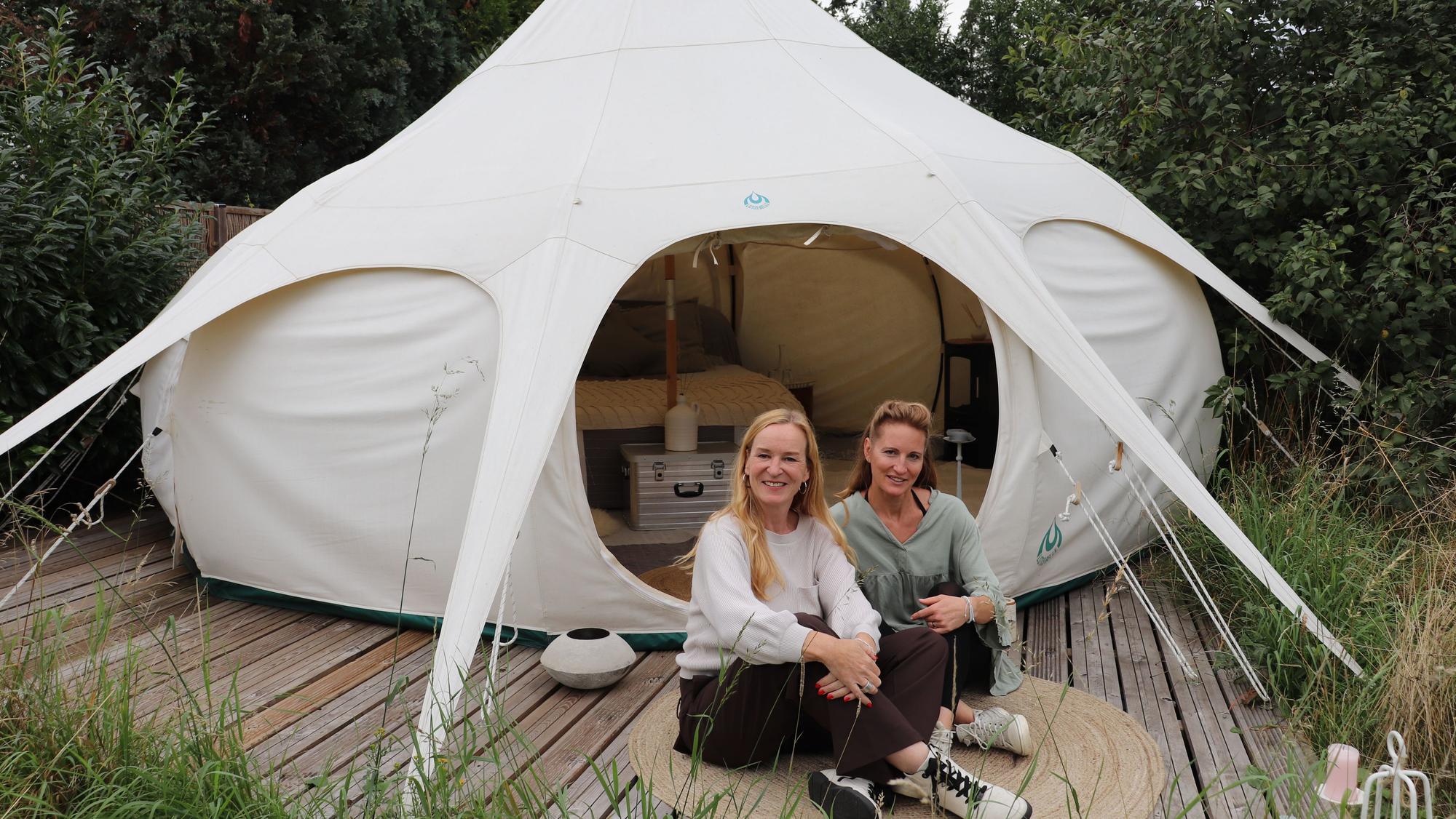 Die beiden Frauen sitzen vor dem Zelt.