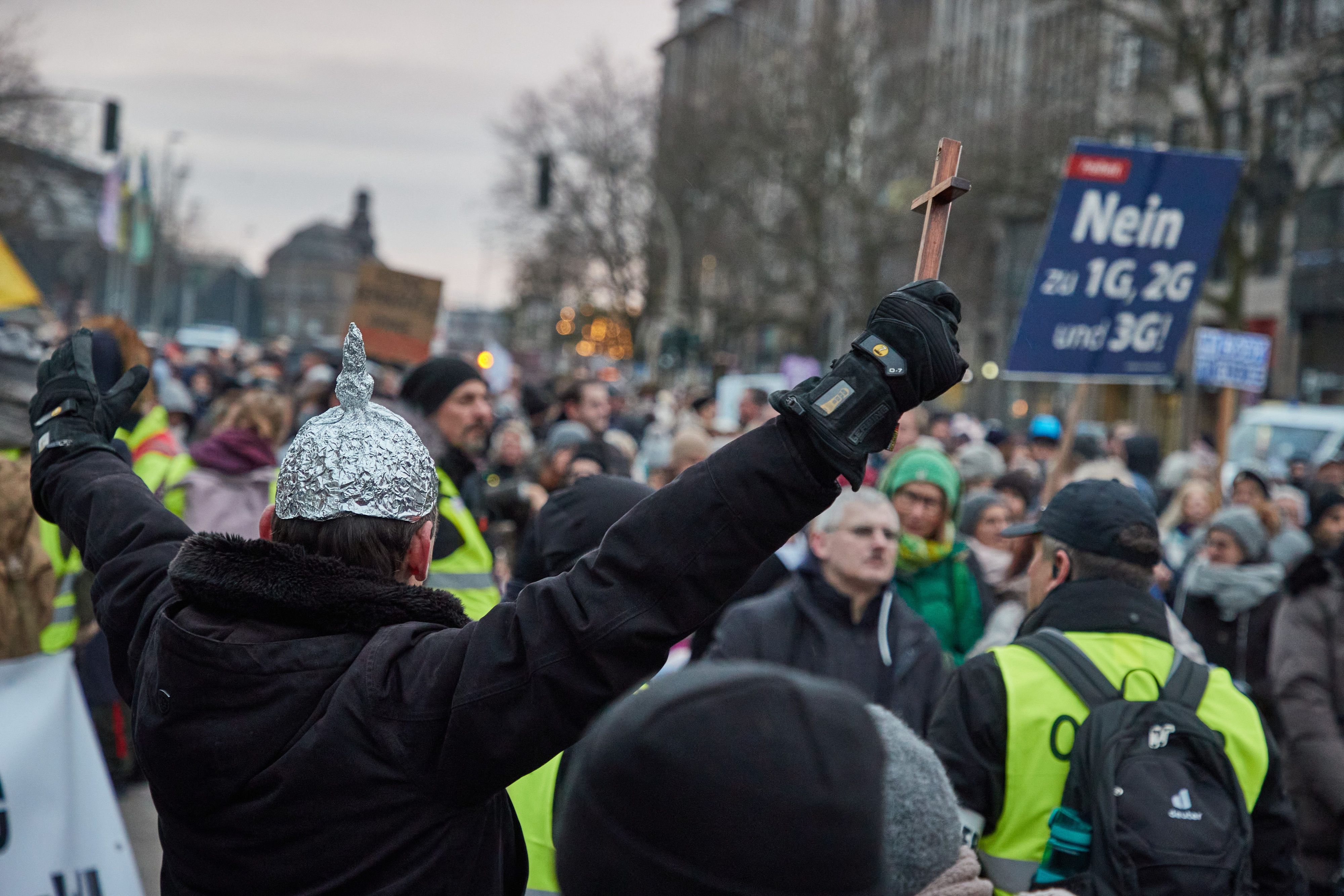 Ein Teilnehmer einer Demonstration gegen Corona-Maßnahmen trägt einen «Aluhut» auf dem Kopf und hält ein Holzkreuz in der Hand. Der Demonstrationszug unter dem Motto «Das Maß ist voll. Hände weg von unseren Kindern» verlief durch die Innenstadt.