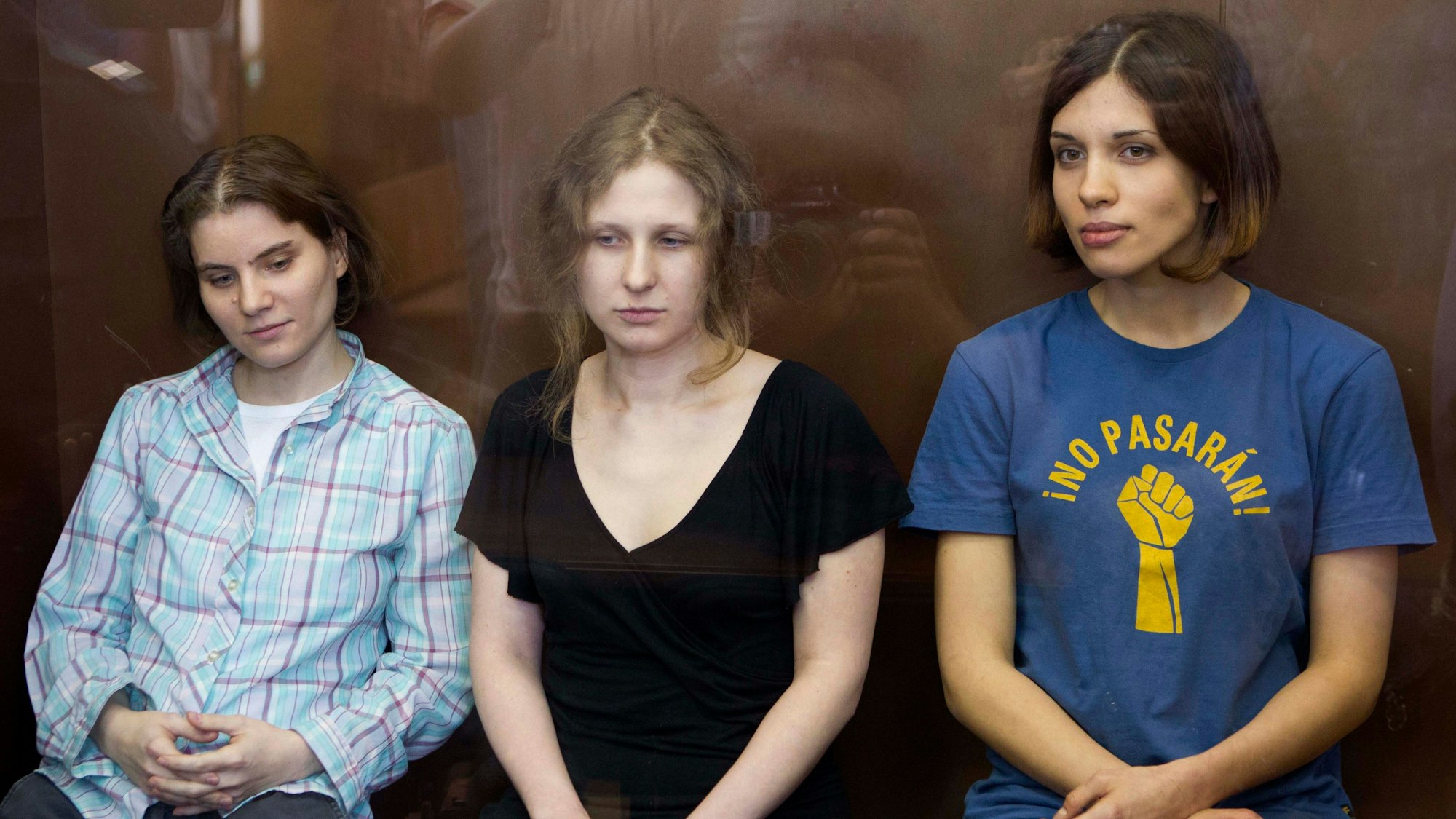 Die Mitglieder der feministischen Punkrockband 'Pussy Riot' (v.l.) Jekaterina Samuzewitsch, Maria Alekhina und Nadeschda Tolokonnikowa sitzen in einem Glaskaefig in einem Gerichtssaal in Moskau.