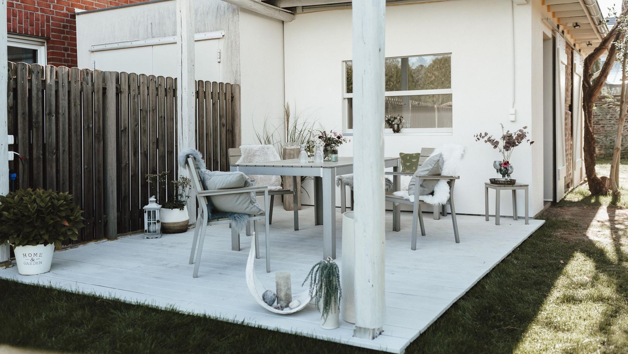 Auf einer Terrasse stehen Tische und Stühle.