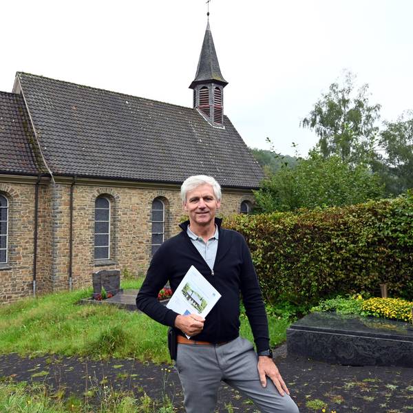Der Makler Christoph Langer ist mit dem Verkauf der katholischen Kirche in der Morsbacher Ortschaft Ellingen beauftragt. Zum Grundstück gehört auch ein Teil des Friedhofs, auf dem der Reichshofer hier steht. In den Händen hält er das Exposé dieser ungewöhnlichen Immobilie.