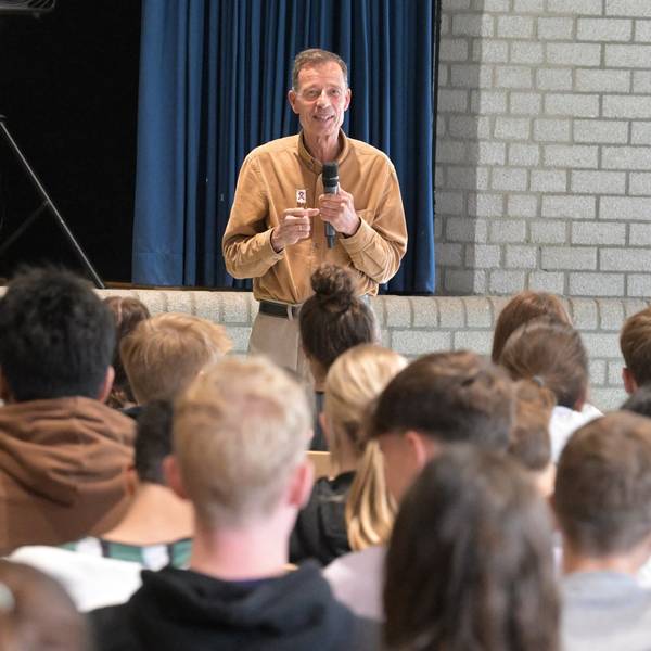 Der Autor Lutz van Dijk steht mit einem Mikrofon in der Hand vor Schülerinnen und Schülern.