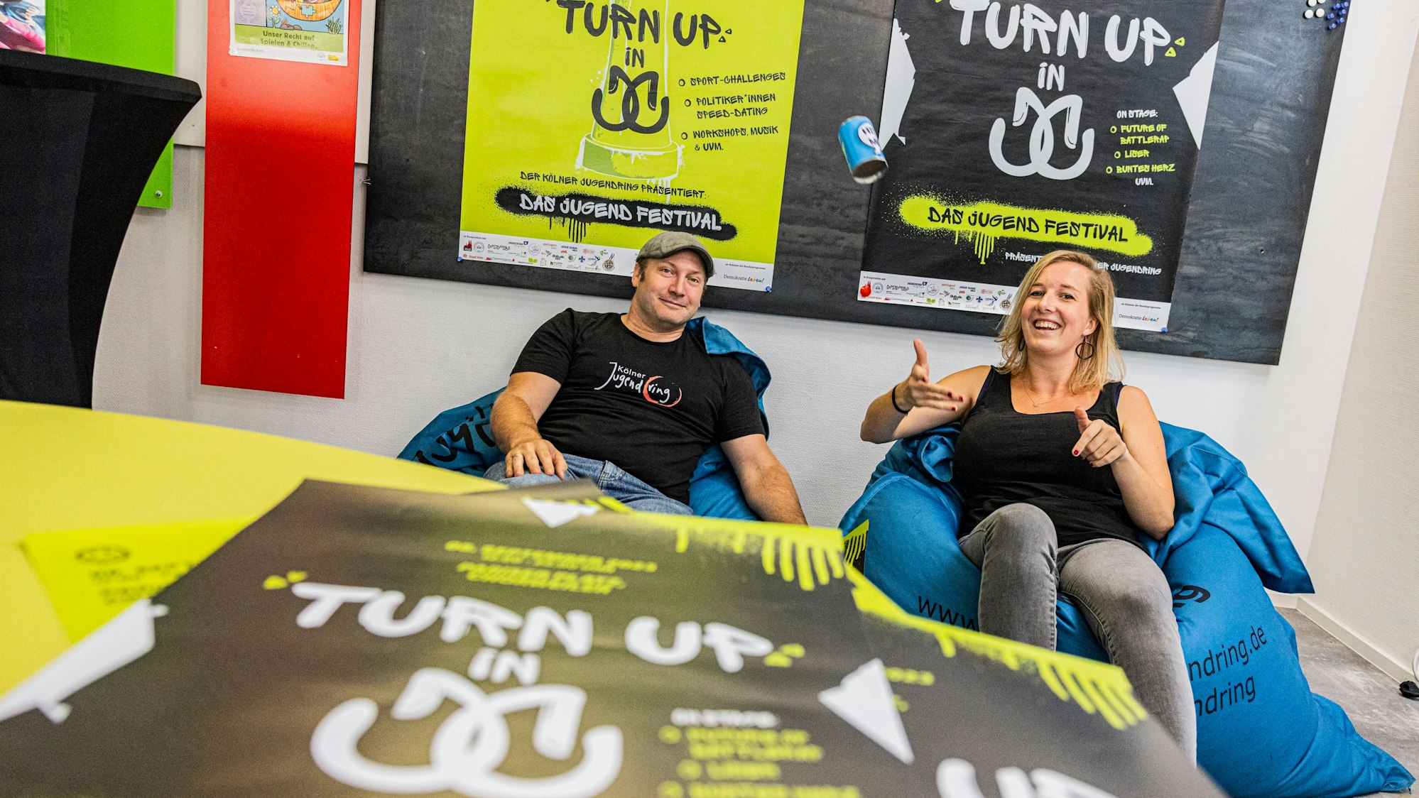 Die Veranstalter des Festivals sitzen auf Sitzsäcken vor Plakaten