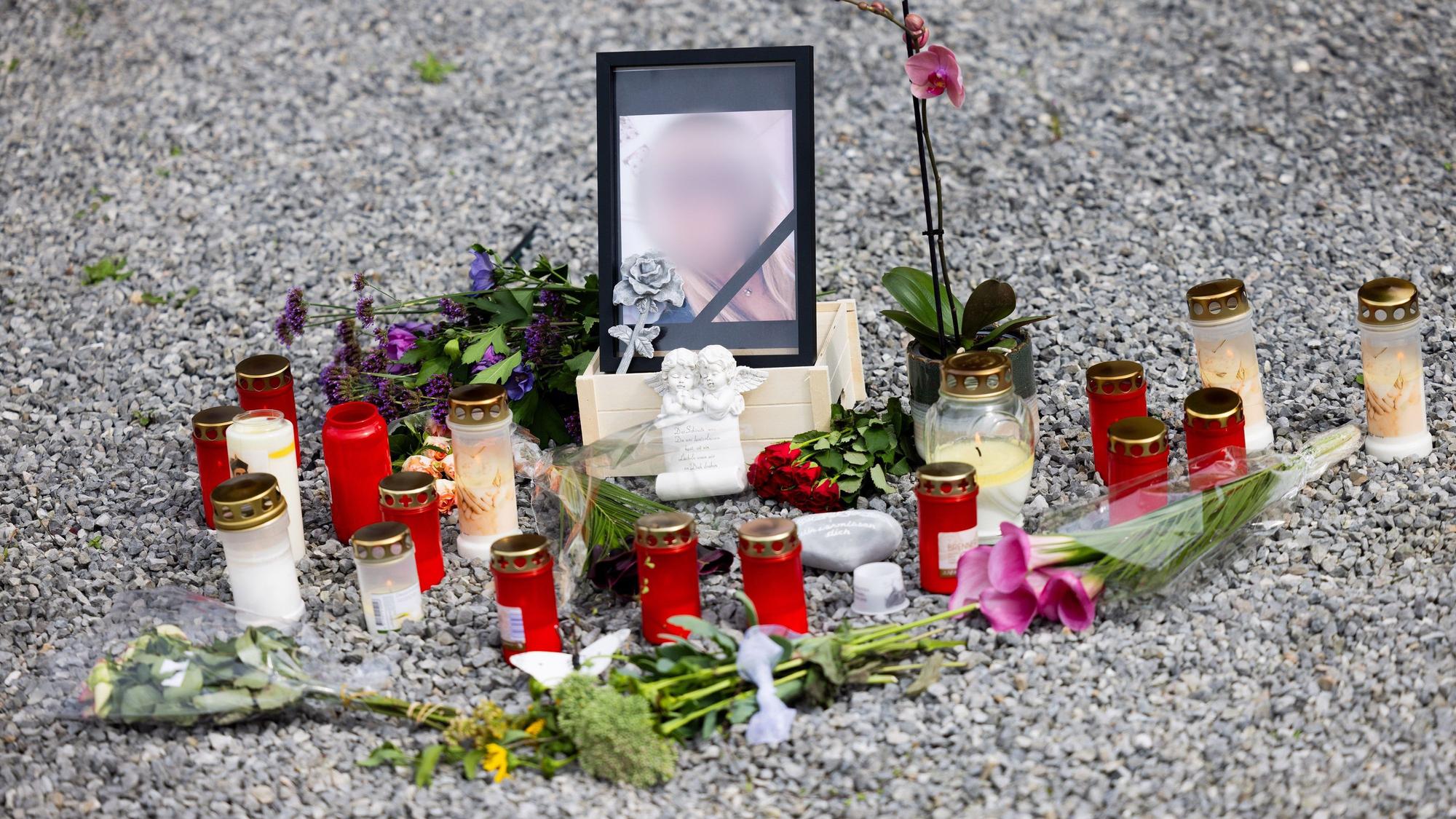 Blumen, Kerzen und ein Foto stehen vor dem Haus.