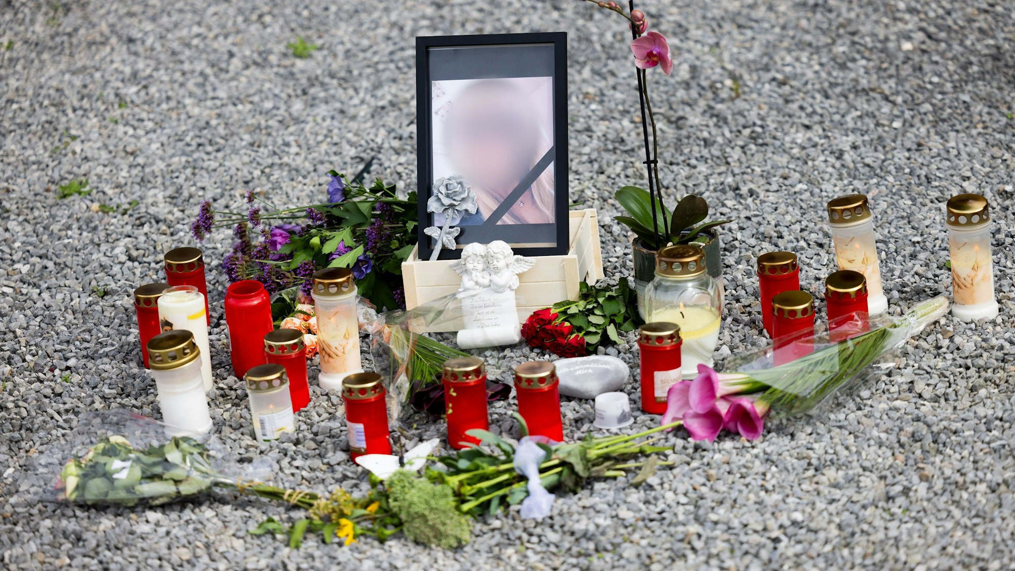 Blumen, Kerzen und ein Foto stehen vor dem Haus.