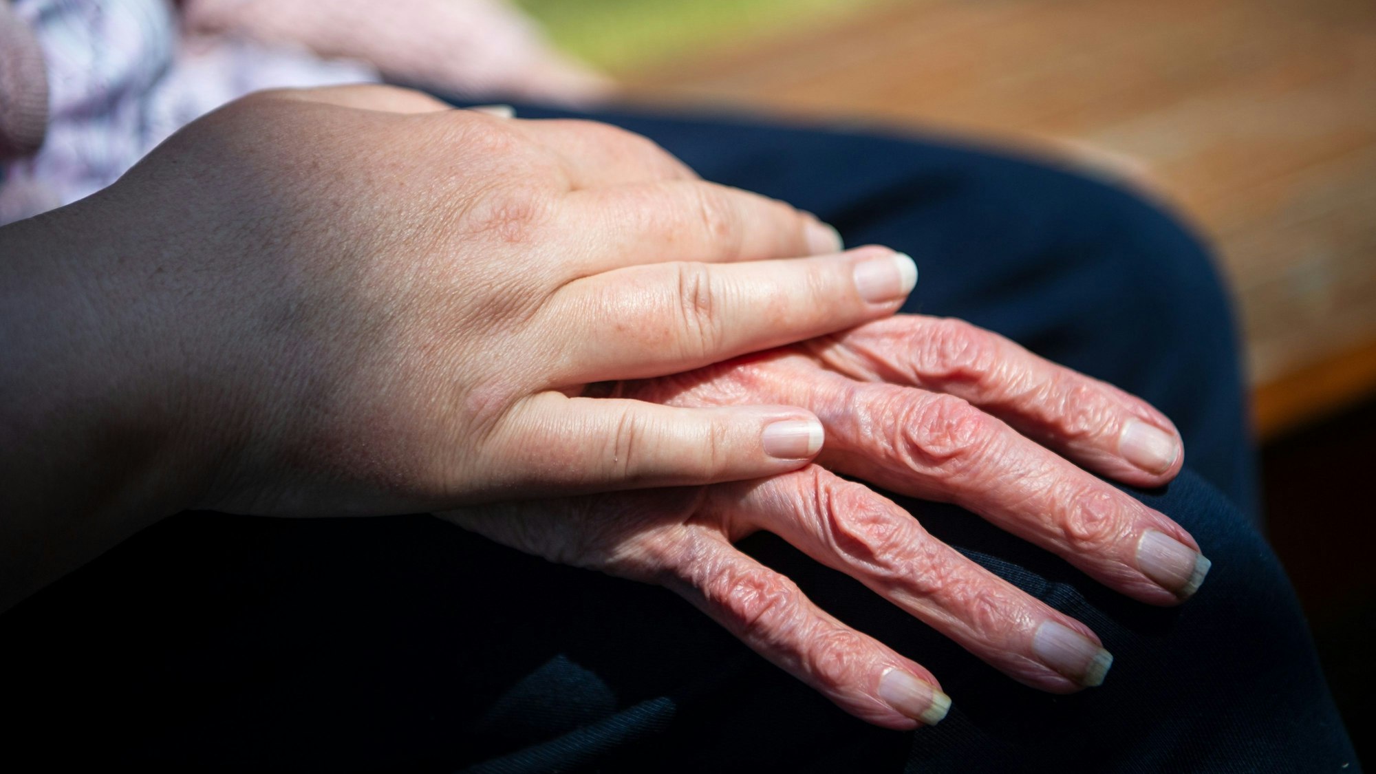 ARCHIV - 16.06.2021, Niedersachsen, Nienburg: Die Hand einer Pflegefachkraft liegt auf der Hand einer Bewohnerin eines Seniorenheims. (zu dpa «Sozialminister stellt Pläne für bessere Pflege vor») Foto: Sina Schuldt/dpa +++ dpa-Bildfunk +++