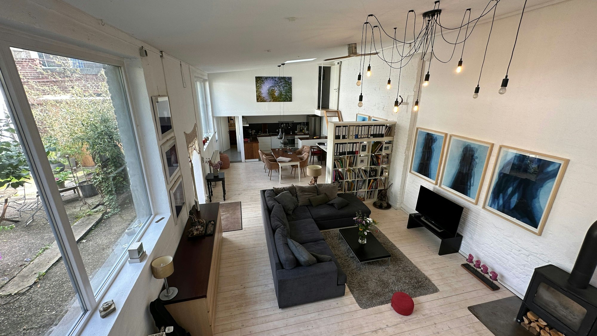 Ein großer offener Wohn- und Arbeitsraum mit sehr großen Fenstern ist von oben fotografiert.