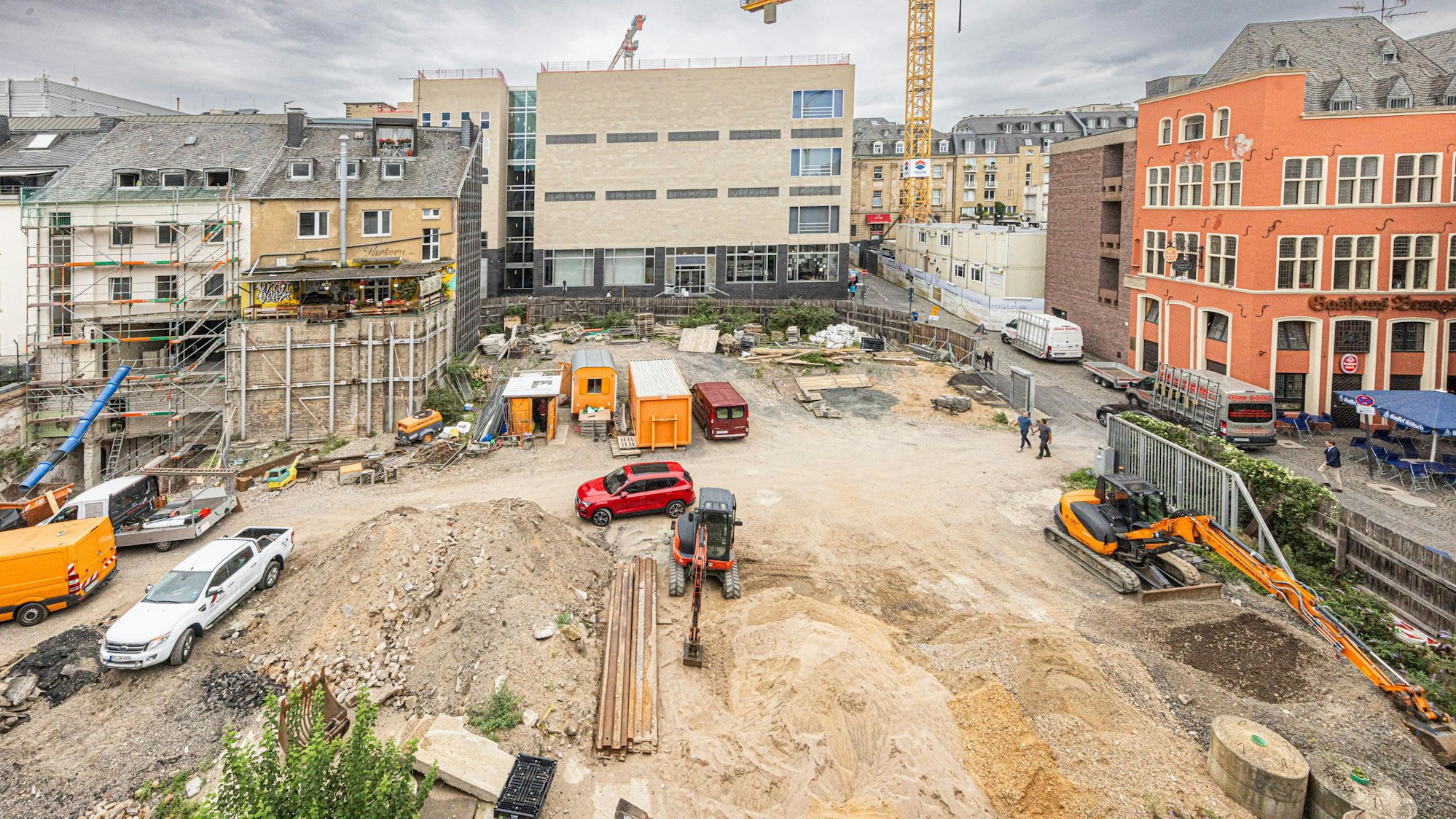 Auf einem Gelände ist Sand verteilt und mehrere Baufahrzeuge stehen rum.