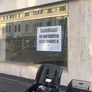 Blick auf ein leeres Ladenlokal, im Schaufenster hängt ein Schild: zu vermieten