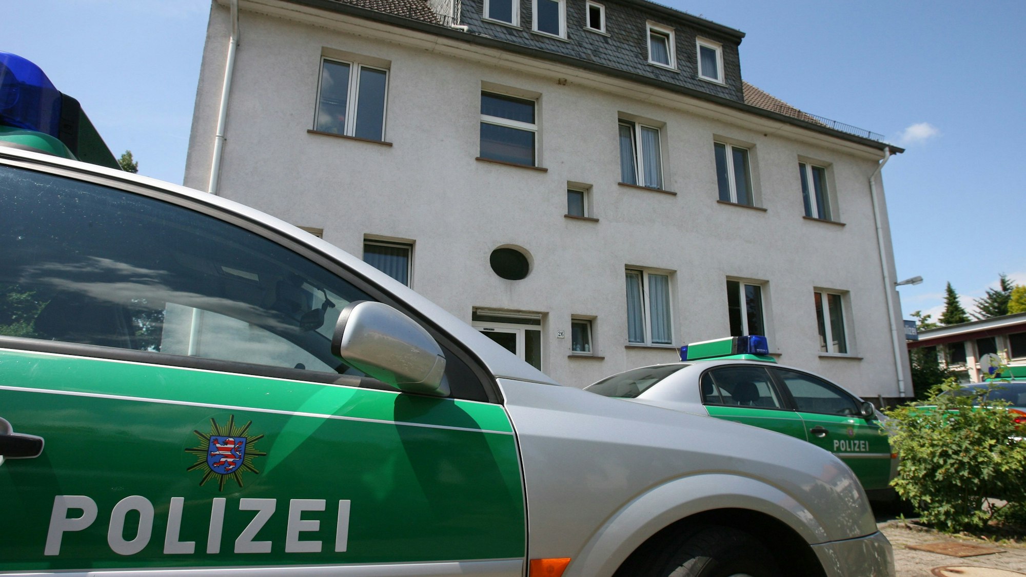 Streifenwagen stehen vor einem Gebäude.
