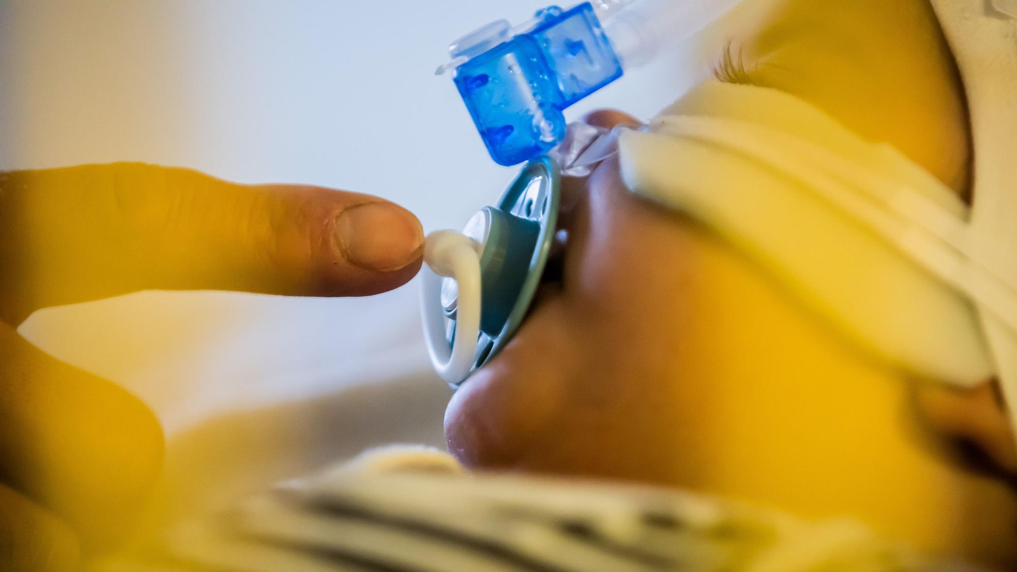 Ein Vater betreut seinen kleinen Sohn, der mit einem Atemwegsinfekt auf der Intensivstation einer Kinderklinik liegt und non-invasiv beatmet wird.