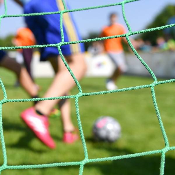 Kinder spielen auf einem Sportplatz Fußball.