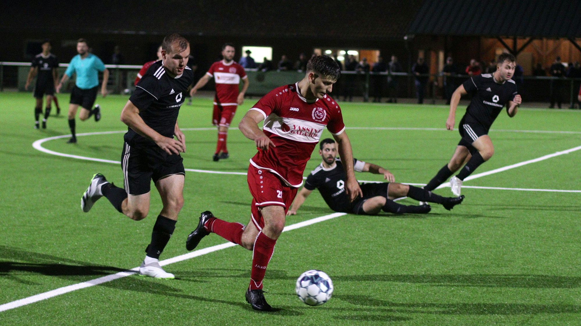 Ein Fußballspieler führt einen Ball und wird vom Gegner verfolgt.