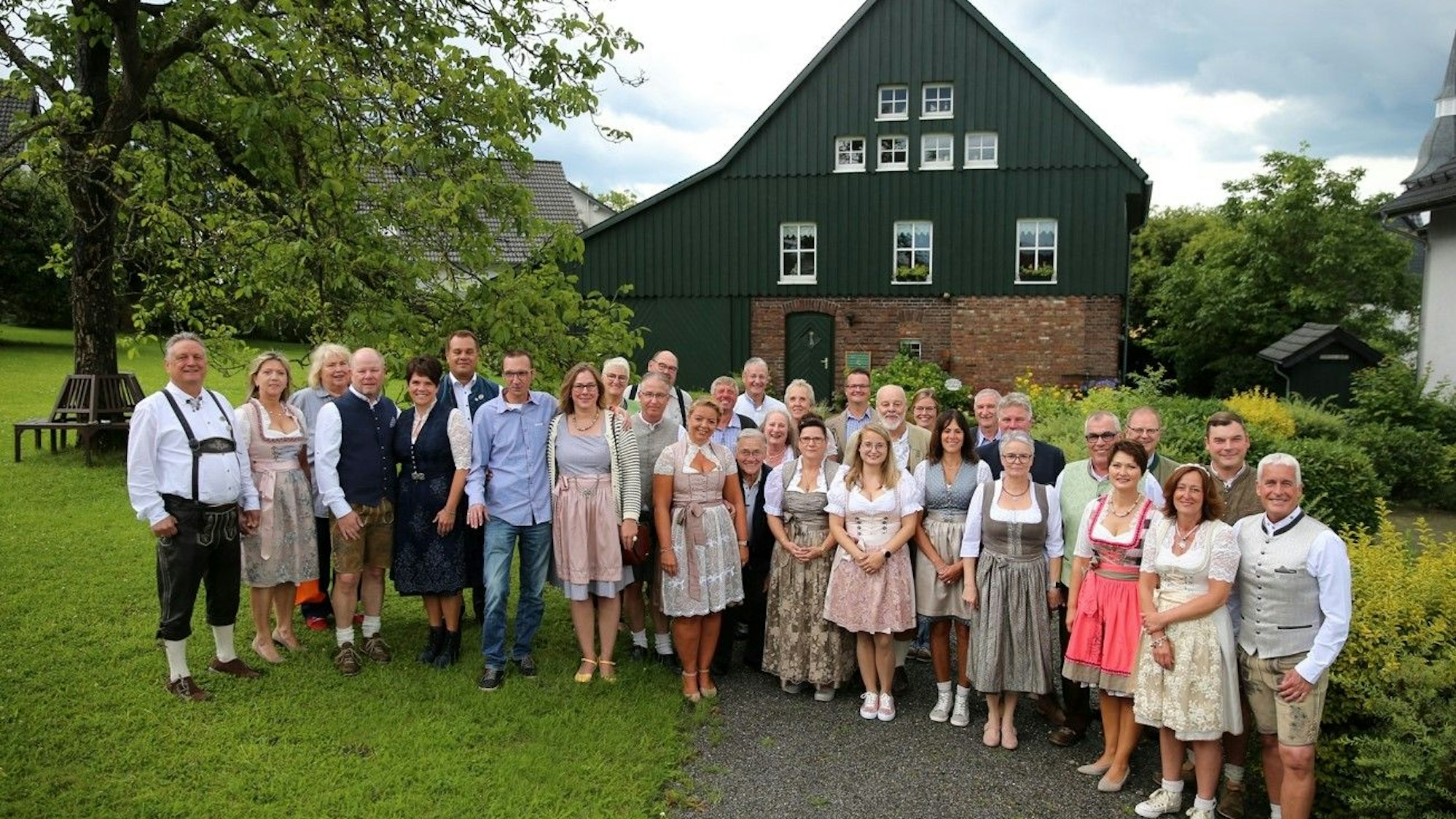 Eine Gruppe von etwa 40 Personen, teils in Tracht, steht vor einem alten Gebäude.