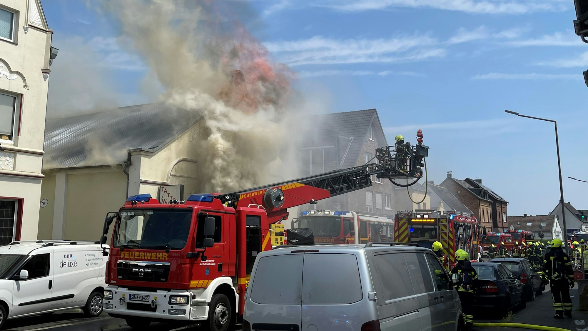 Mit einer Drehleiter löschen Feuerwehrleute Flammen, die aus einem Gebäude schlagen.
