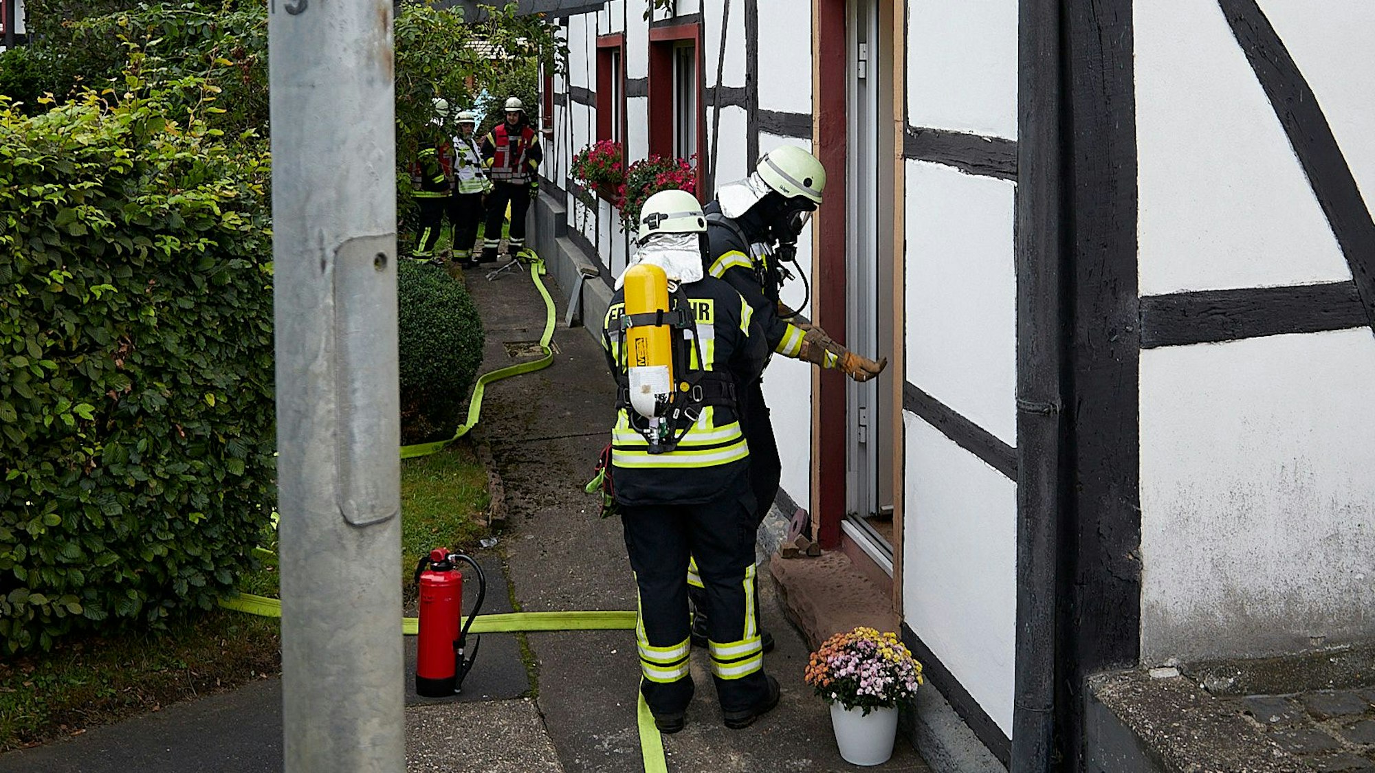 Feuerwehrleute stehen an der Tür eines Fachwerkhauses.