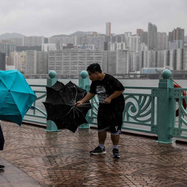 TOPSHOT - People struggle with their umbrellas in high winds brought by Super Typhoon Saola next to Victoria harbour in Hong Kong on September 1, 2023. Super Typhoon Saola threatened southern China on September 1 with some of the strongest winds the region has endured, forcing the megacities of Hong Kong and Shenzhen to effectively shut down. (Photo by ISAAC LAWRENCE / AFP)
