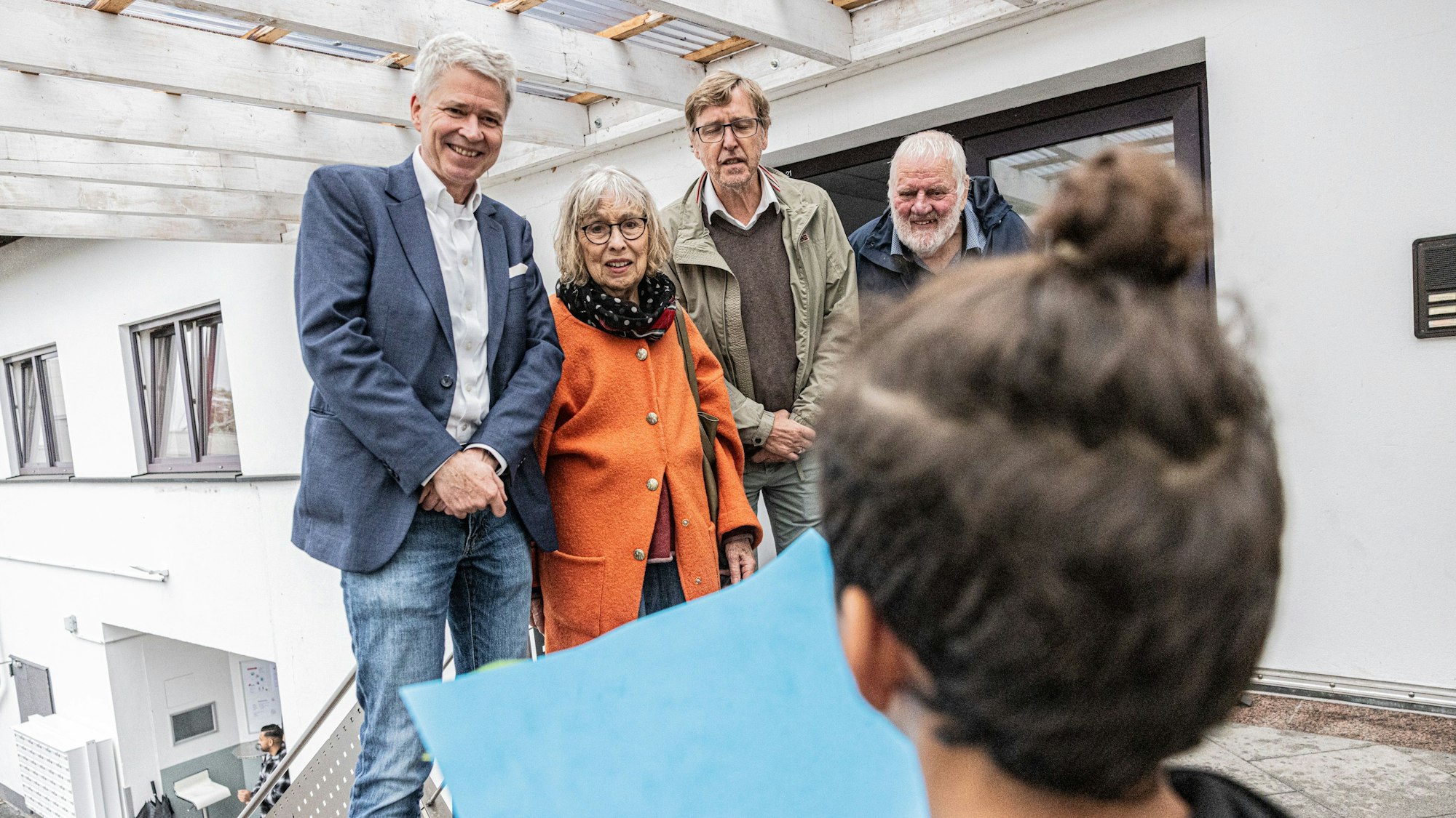 Stolz präsentiert ein kleiner Junge sein beim Sommerfest der Geflüchtetenunterkunft gemaltes Bild. Sozialdezernent Harald Rau, Roswitha Bethe, Caritaschef Peter Krücker und Erich Bethe (v.l.l) nehmen es genau in Augenschein.