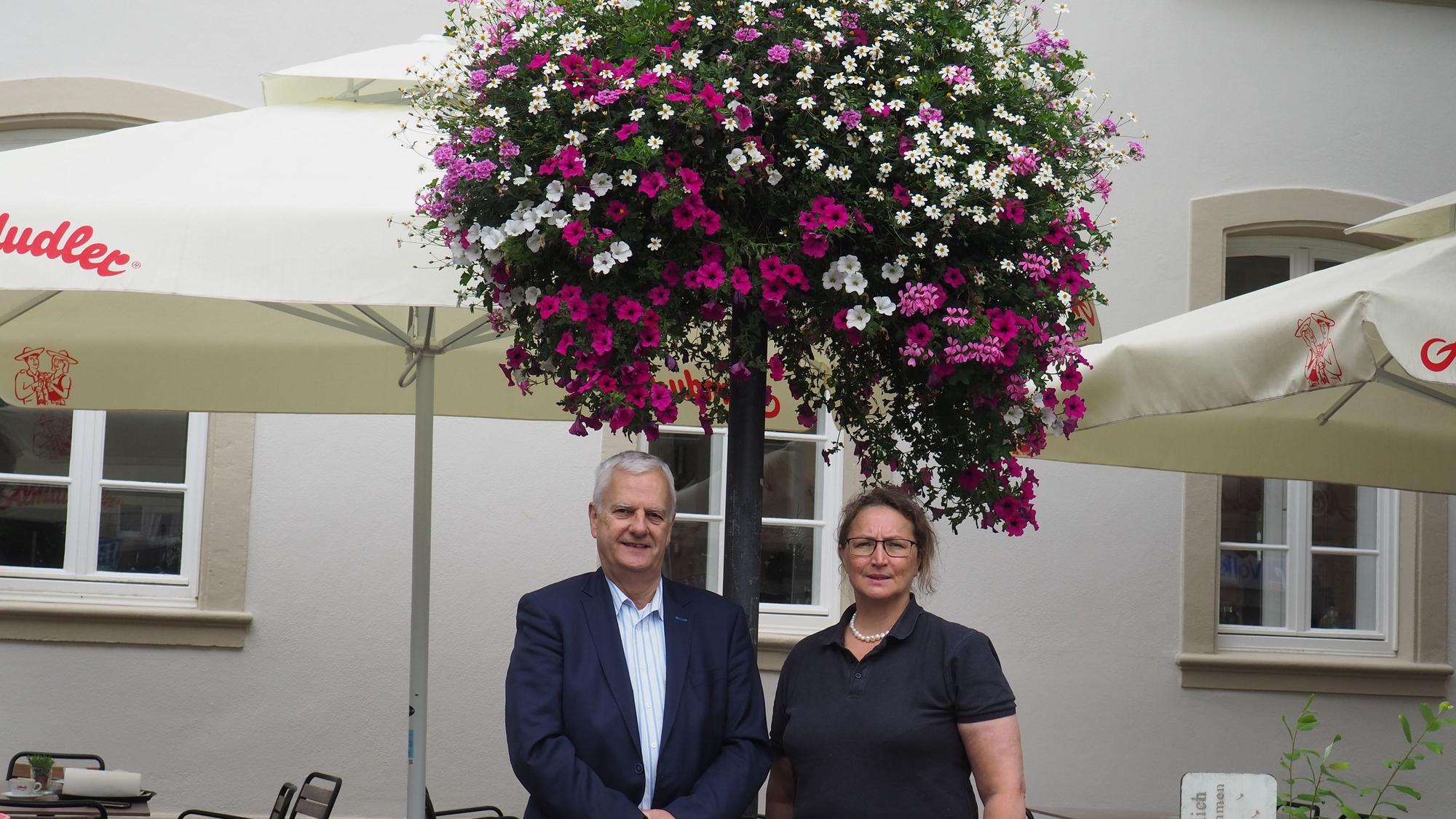 Ein Mann und eine Frau stehen unter einer üppigen Blumenampel.